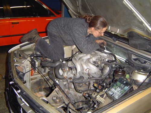 Im Motorraum eines BMW 525e: Textmechanikerin Elisabeth Strassert beim Schrauben statt Schreiben